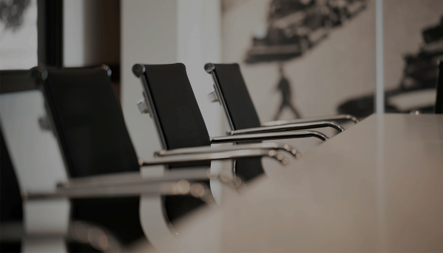 Empty black chairs pulled up to conference table