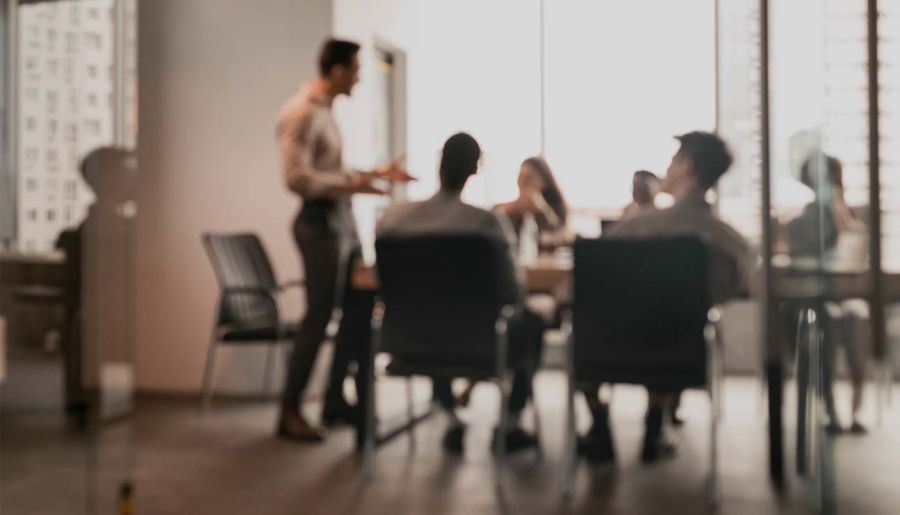 Colleagues having meeting in boardroom, businessman giving speech, blurred photo stock